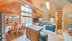 L’intérieur d’une cabane en bois comprend un coin repas, une cuisine, un salon et une cheminée.