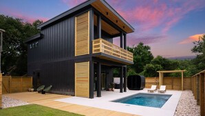A modern two-story house with a balcony, a swimming pool, and a wooden deck.