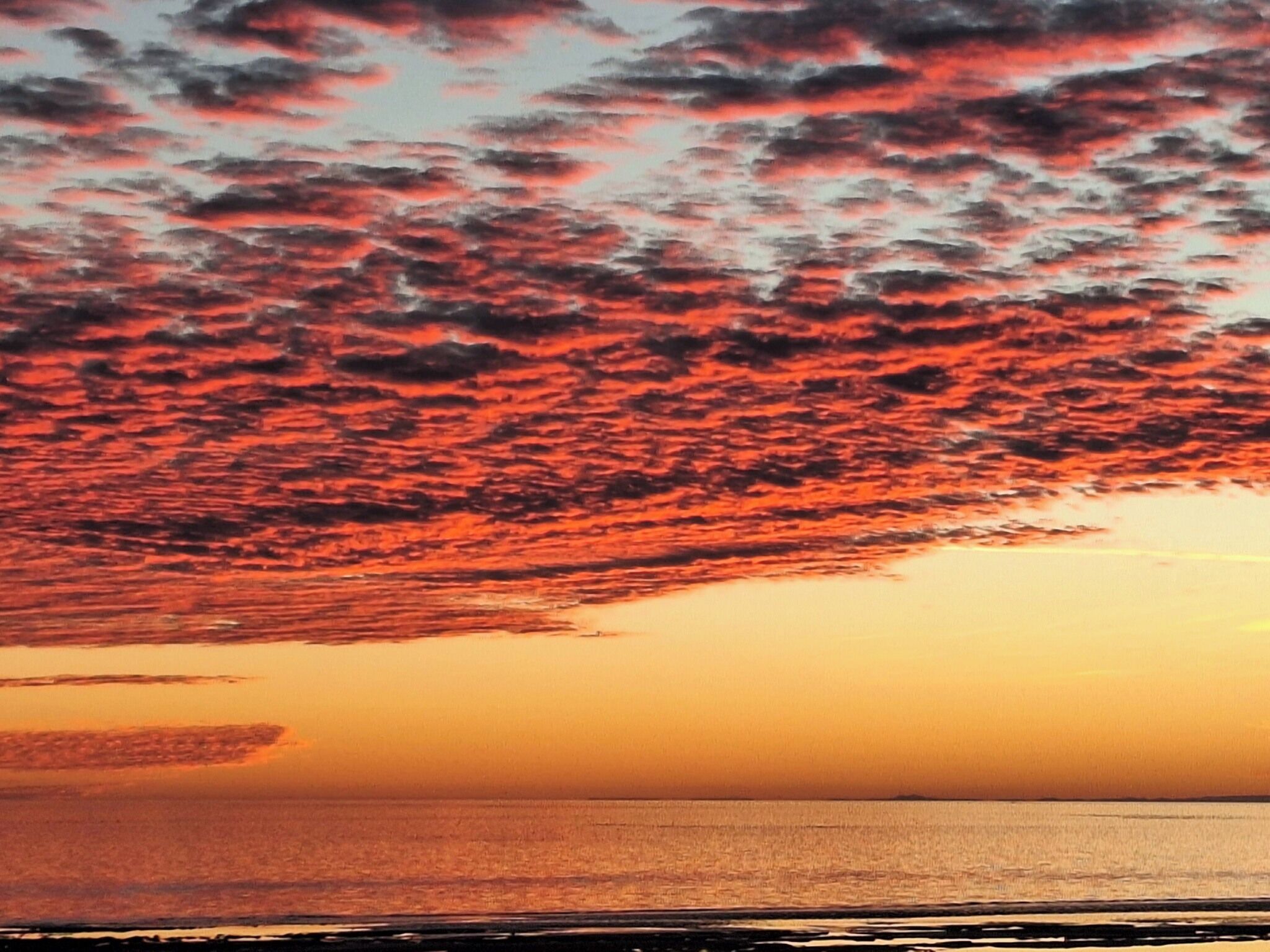 Ein Sonnenuntergang über dem Meer bei klarem Himmel.