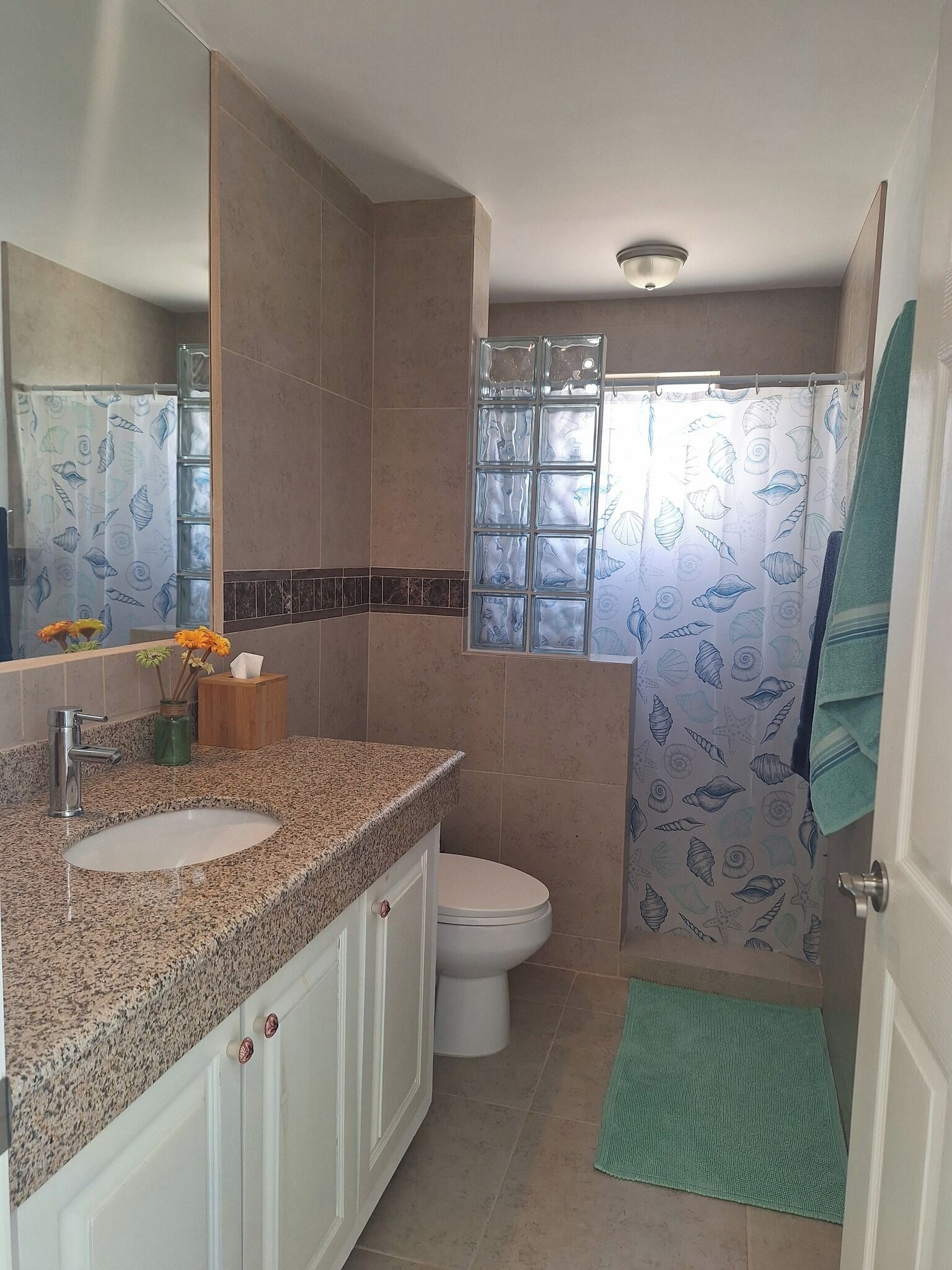 Ein Badezimmer mit einer Granitplatte, zwei Waschbecken, einer Toilette und einer Dusche mit Glastür.