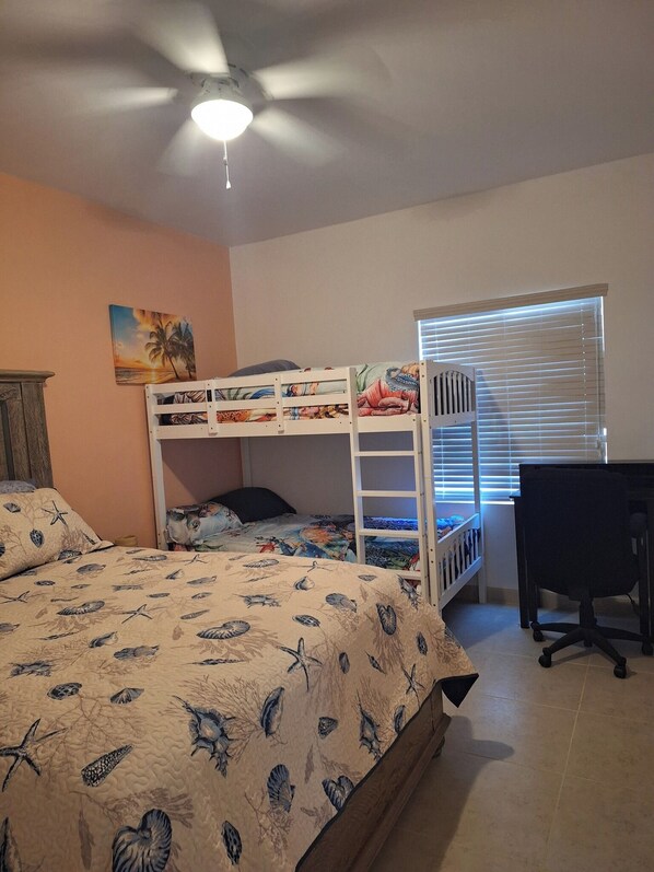 Un dormitorio con literas, un escritorio y un ventilador de techo.