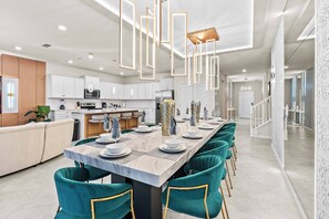 Una cocina moderna con armarios blancos, una isla central y sillas color turquesa.