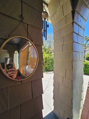 A circular mirror on a wall with a view of a paved pathway and greenery in the background.