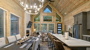 A spacious kitchen with a large island, built-in appliances, and a high ceiling with exposed beams.