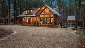 A log cabin with a large deck, a covered porch, and a fireplace.