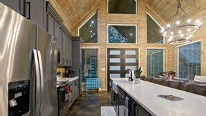 A modern kitchen with stainless steel appliances, a large island, and a dining area with a sofa.