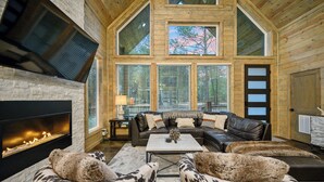 A spacious living room with a fireplace, leather furniture, and large windows.