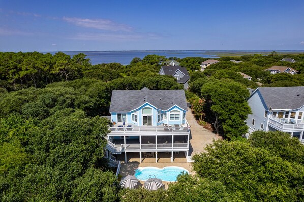 A large, two-story house with a swimming pool and a view of the ocean.