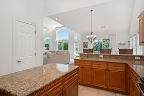 A spacious kitchen with granite countertops, wooden cabinets, and a large island.