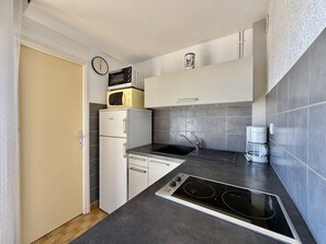 Een koelkast, een oven, kookgerei, borden en bestek