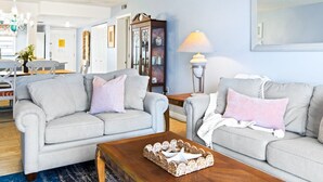 A living room with two grey sofas, a wooden coffee table, and a lamp. - Cocoa Beach Oceanfront | Sunrise Views, Heated Pool & BBQ Grill | Walk to Downtown (Cocoa Beach)