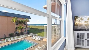 A balcony with a pool, lounge chairs, and a view of the ocean. - Cocoa Beach Oceanfront | Sunrise Views, Heated Pool & BBQ Grill | Walk to Downtown (Cocoa Beach)