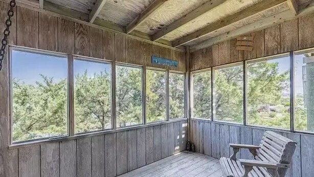 Una habitación con paneles de madera, ventanas amplias, un banco y un letrero con un número de habitación.