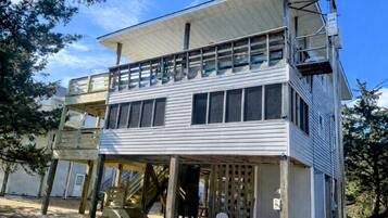 A two-story building with a balcony on the upper floor, a staircase leading to the upper level, and a covered outdoor area with chairs.