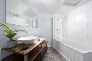 A modern bathroom with a white sink, a wooden vanity, a large mirror, and a glass-enclosed shower. - Berlewen  -  a cottage that sleeps 6 guests  in 3 bedrooms (Mousehole)