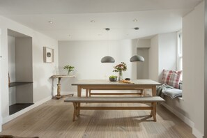 A modern kitchen with a wooden bench, pendant lights, and a dining table. - Berlewen  -  a cottage that sleeps 6 guests  in 3 bedrooms (Mousehole)