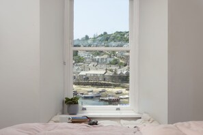 A bedroom with a large window overlooking a harbor with boats and houses. - Berlewen  -  a cottage that sleeps 6 guests  in 3 bedrooms (Mousehole)
