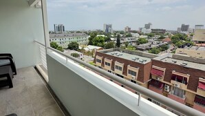 Un balcon offrant une vue sur le paysage urbain, avec des bâtiments et un ciel dégagé.