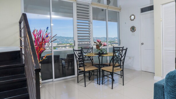 Un balcon avec une table et des chaises pour prendre les repas, une vue sur le paysage urbain et une porte dotée d’un miroir.