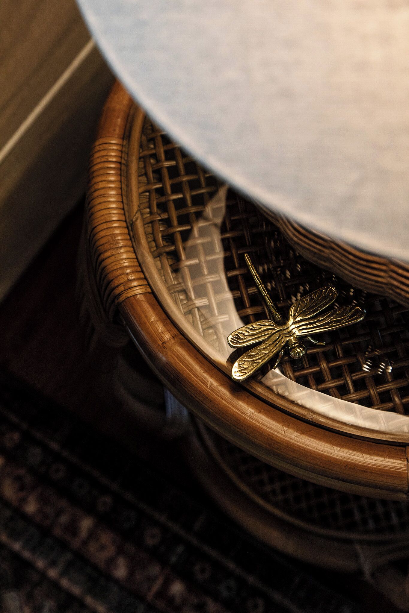 A wicker chair with a decorative metal dragonfly ornament.