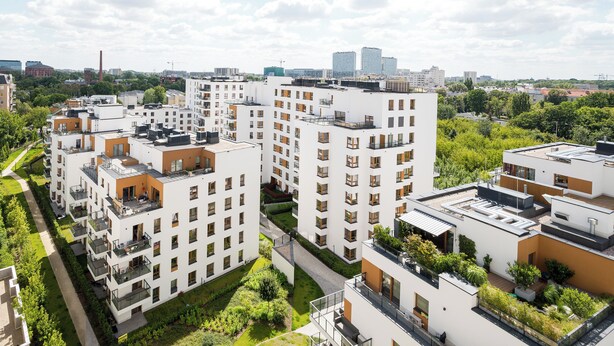 A modern apartment complex with multiple buildings, balconies, and green spaces.