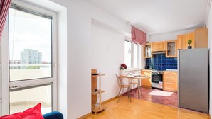A modern kitchen with wooden cabinets, a stainless steel refrigerator, and a dining area with a table and chairs.