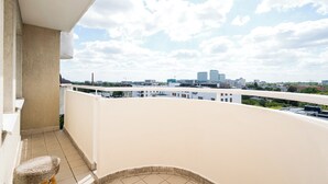 A balcony with a view of a cityscape, including buildings and a clear sky.