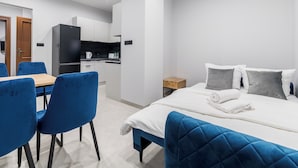 Et moderne hotelværelse med en seng, et lille skrivebord og et tekøkken.