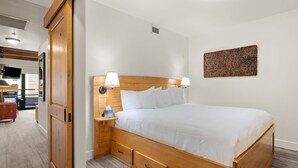 A neatly arranged hotel room with a wooden bed, bedside lamps, a small bedside table, and a wall-mounted artwork.