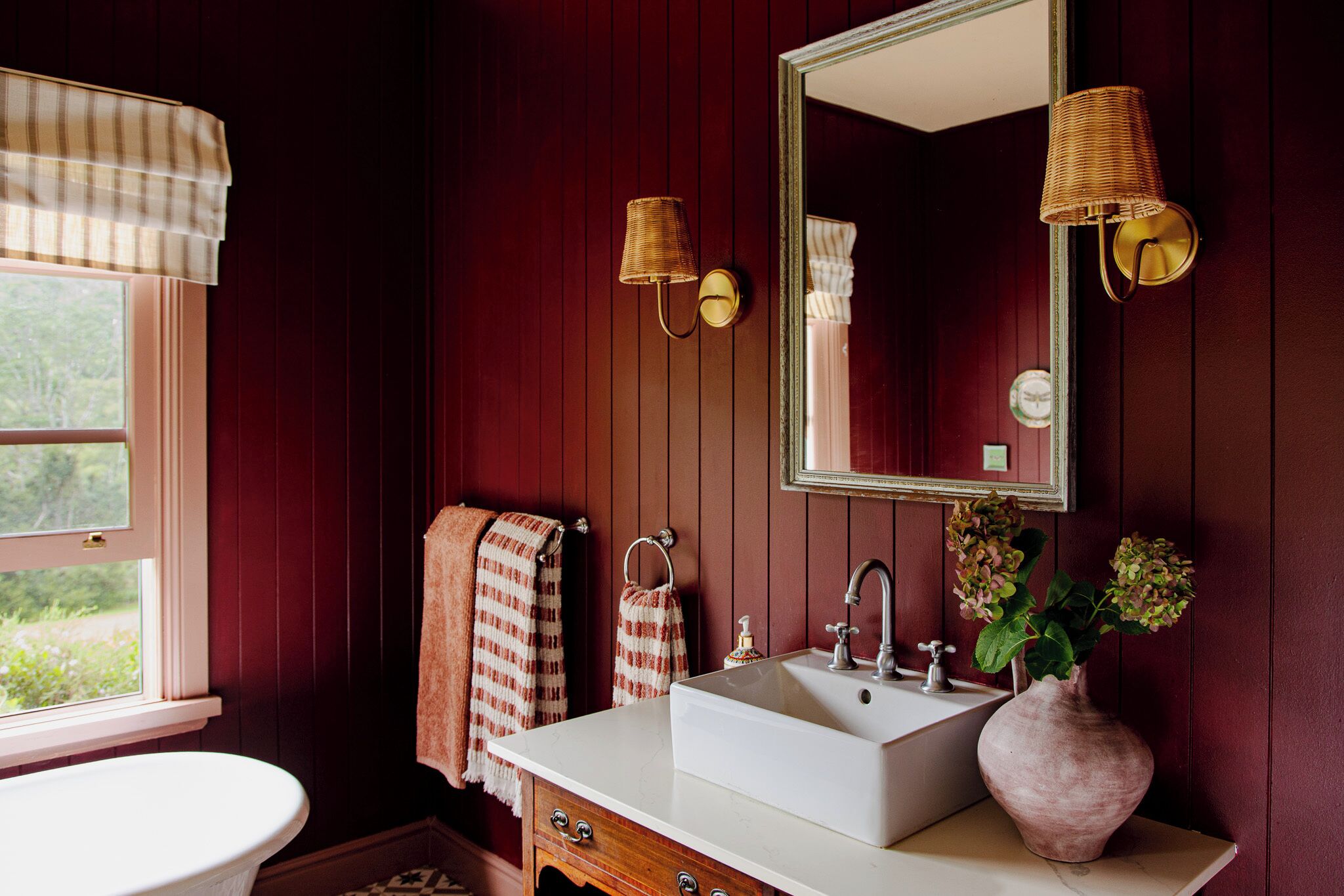 Ein Badezimmer mit einem weißen Waschbecken, einem Spiegel und zwei Wandleuchten.