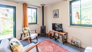 Een gezellige woonkamer met een open haard, een televisie en een comfortabele zithoek.