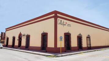 A building with a beige facade and red trim, featuring the sign 'Collection Zapata Hotel & Plaza'.