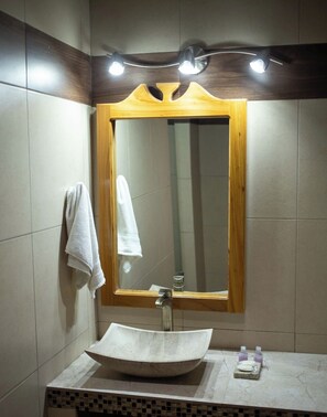 Une salle de bain avec un grand miroir, un lavabo sur colonne et une serviette accrochée au mur.