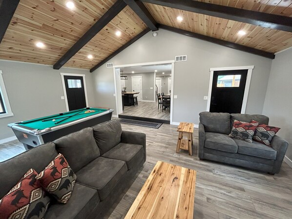A spacious living area with a pool table, two sofas, and a coffee table. - The Farmhouse at Rustic Ridge (Benzonia)
