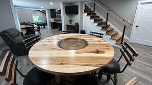 Ein moderner Essbereich mit einem runden Holztisch und schwarzen Stühlen, einer Treppe mit Holzstufen sowie einer Küche im Hintergrund.