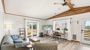 A spacious living room with a ceiling fan, a sofa, a coffee table, and a TV. - Sandy Keys 1 *Pet Friendly*2min walk to beach! (Kill Devil Hills)