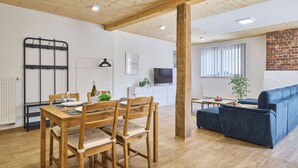 A modern living space with a dining area, a sofa, a TV, and a brick wall. - Lovely apartment for 4 guests with pool, WIFI, TV and patio (Železný Brod)