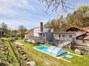 A residential area with a swimming pool, a covered patio, and a stone wall.
