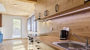A modern kitchen with wooden cabinets, a stainless steel sink, and a kettle. - Lovely apartment for 4 guests with pool, WIFI, TV and patio (Železný Brod)