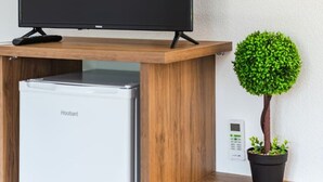 A flat-screen TV on a wooden stand, a white refrigerator, and a potted plant. - Bliss Studio Free Parking Wifi (Lazarat)