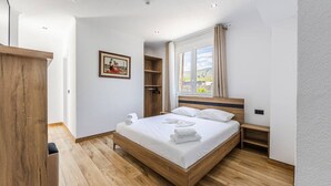 A bedroom with a wooden bed, white linens, a wooden wardrobe, a framed picture on the wall, and a window with curtains. - Bliss Studio Free Parking Wifi (Lazarat)