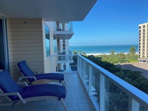 Ein Balkon mit zwei Loungestühlen, freier Blick auf den Strand und ein Hochhaus im Hintergrund.