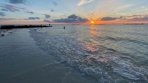 A beach with calm waters, a visible horizon, and a sunset. - Marriott's Crystal Shores - 2 bedroom luxury villa on Crescent Beach in Marco (Marco Island)