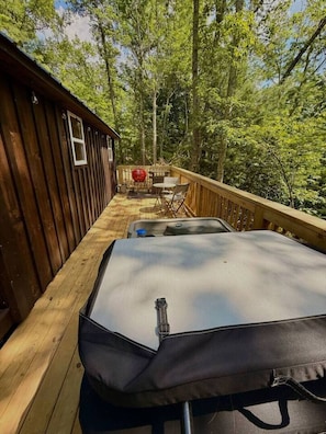 A wooden deck with a covered seating area, a grill, and a small table. - Adventurer’s Nook | Tiny Home w/ Hot Tub & Firepit (Campton)