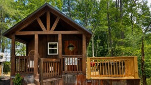 Eine Holzhütte mit Veranda, einem kleinen Fenster und einer Holzterrasse.