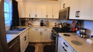 A kitchen with white cabinets, a stove, a microwave, and a coffee maker.