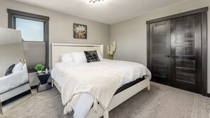 Un dormitorio moderno con una cama grande, una mesita de noche, un espejo y un armario de madera oscura.