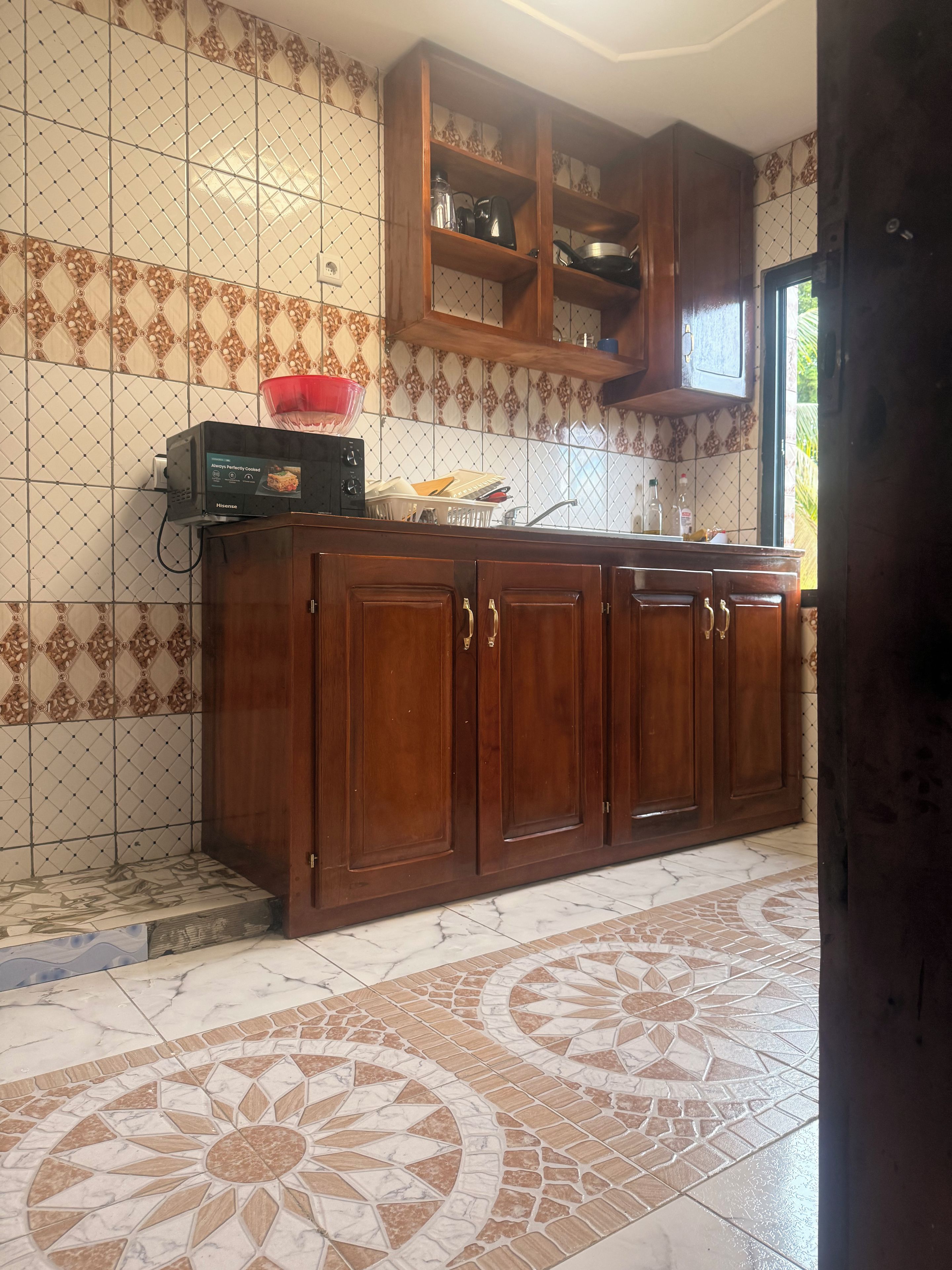 A kitchen with wooden cabinets, a microwave, and a red bowl on the counter.