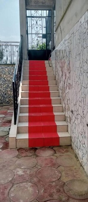 A staircase with red steps leading up to a door with a metal gate. - Appartment and studios in kribi. (Kribi)