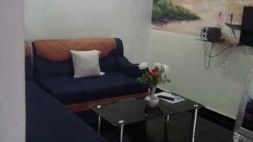 A living room with a blue sofa, a small coffee table, and a painting on the wall.